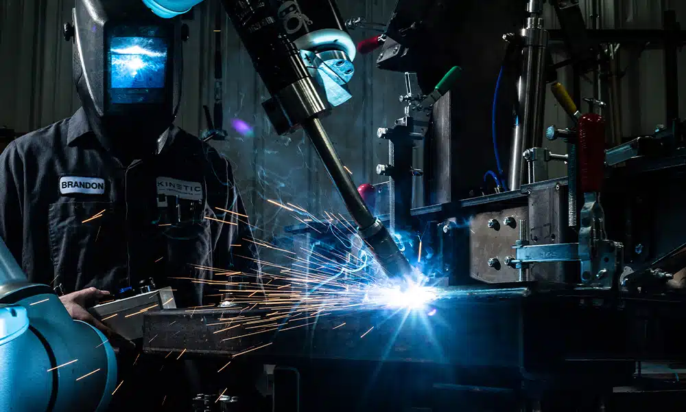 Welder operating a robotic arm for precision welding